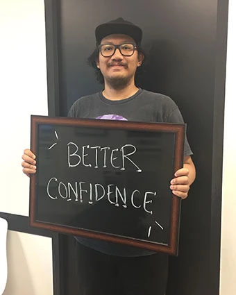 A man holds a sign that reads, "BETTER CONFIDENCE".