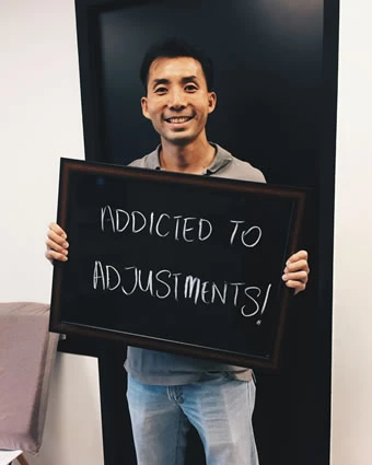 A man holds a sign that reads, "ADDICTED TO ADJUSTMENTS!".