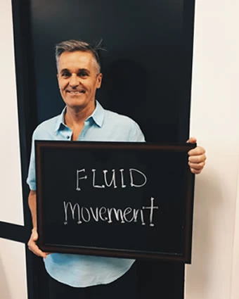 A man holds a sign that reads, "FLUID movement".