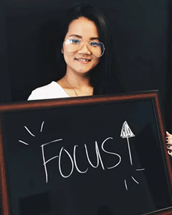 A woman holds a sign that reads, "Focus ↑".