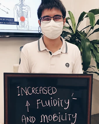 A man in a face mask holds a sign that reads "INCREASED ↑ FLUIDITY AND MOBILITY".
