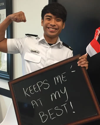 A man flexes his bicep and holds a sign that reads, "KEEPS ME AT MY BEST!".