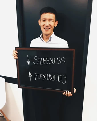 A man holds a sign showing "Reduce stiffness" and "Increase flexibility".