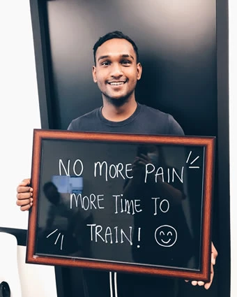 A man holds a sign that reads, "NO MORE PAIN MORE TIME TO TRAIN!".