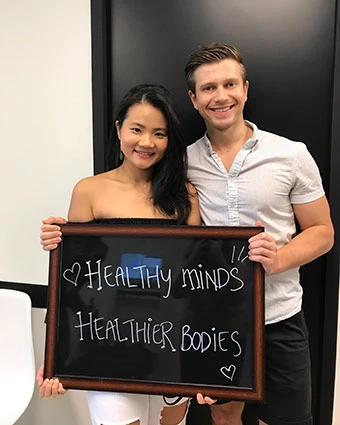 A woman and man hold a sign that reads "Red love emoji Healthy minds Healthier bodies".